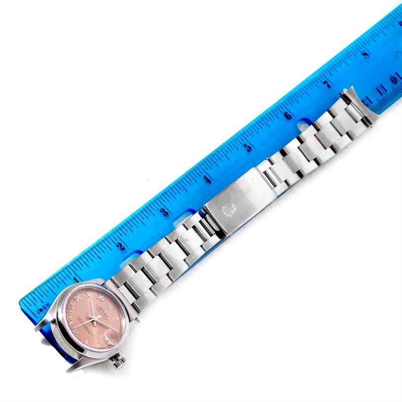 This image shows a Rolex Mid-Size 78240 Women's Stainless Steel Pink Dial 78240 Women's Stainless Steel Pink Dial watch laid flat, with its pink dial, stainless steel bracelet, and clasp, beside a blue ruler.