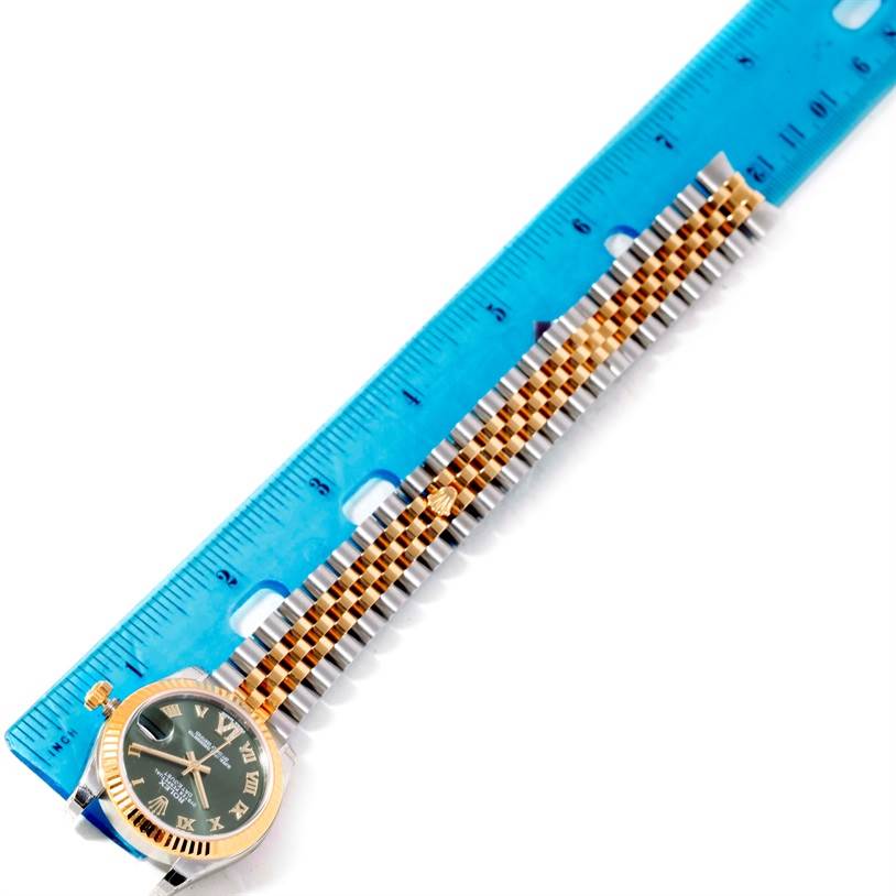 The image shows a top view of a Rolex Mid-Size 178273 Women's Steel and Gold (two tone) Green Dial 178273 Women's Steel and Gold (two tone) Green Dial watch with a gold and silver bracelet next to a blue ruler for measurement.