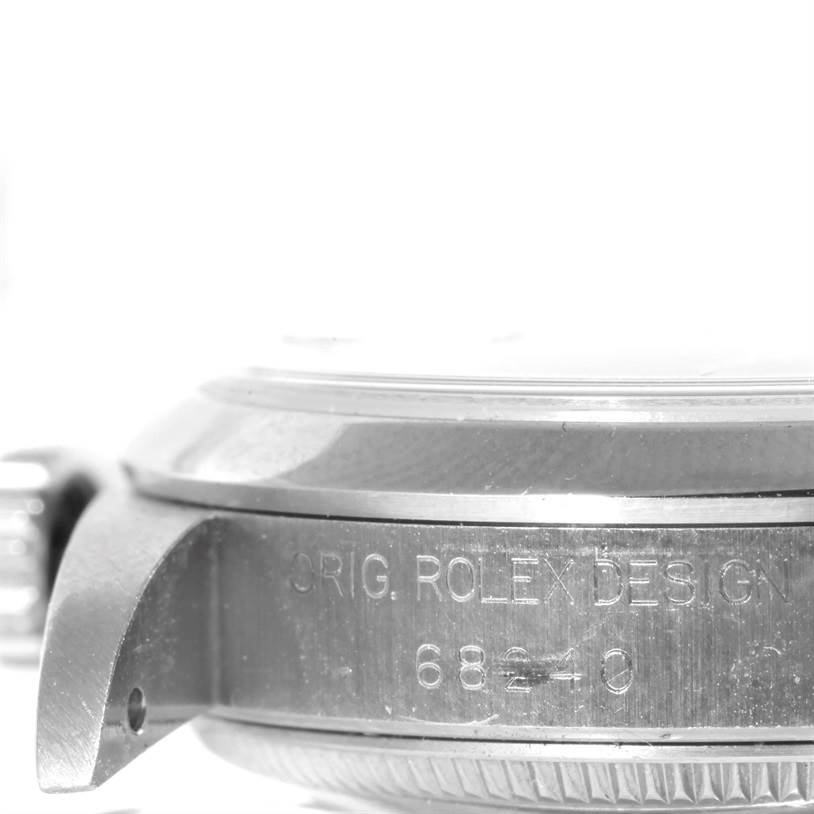 The image shows a close-up of the side of a Rolex Mid-Size 68240 Women's Stainless Steel Blue Dial 68240 Women's Stainless Steel Blue Dial watch, focusing on the casing with visible engravings.