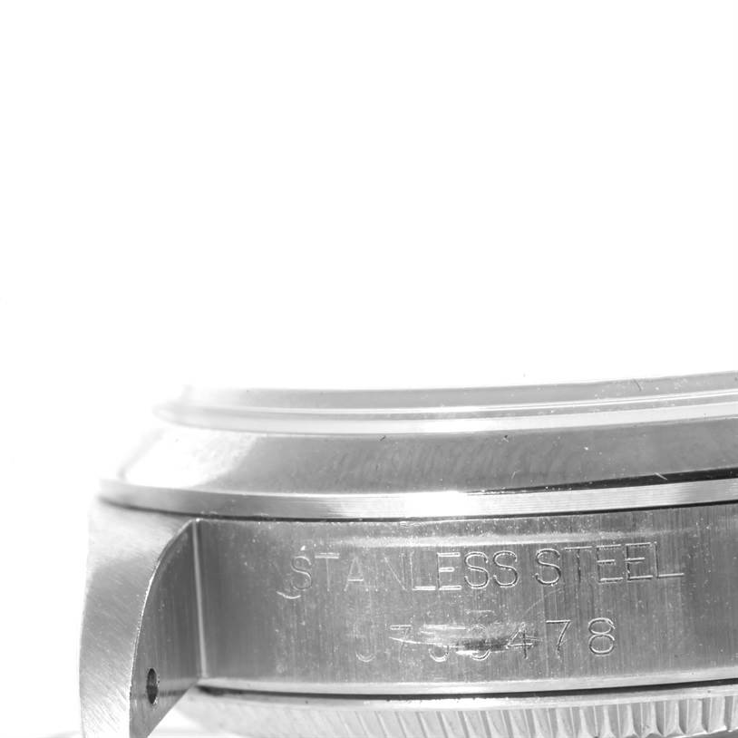 The image shows a close-up side view of a stainless steel model by Rolex, highlighting the engraving on the watch's side.