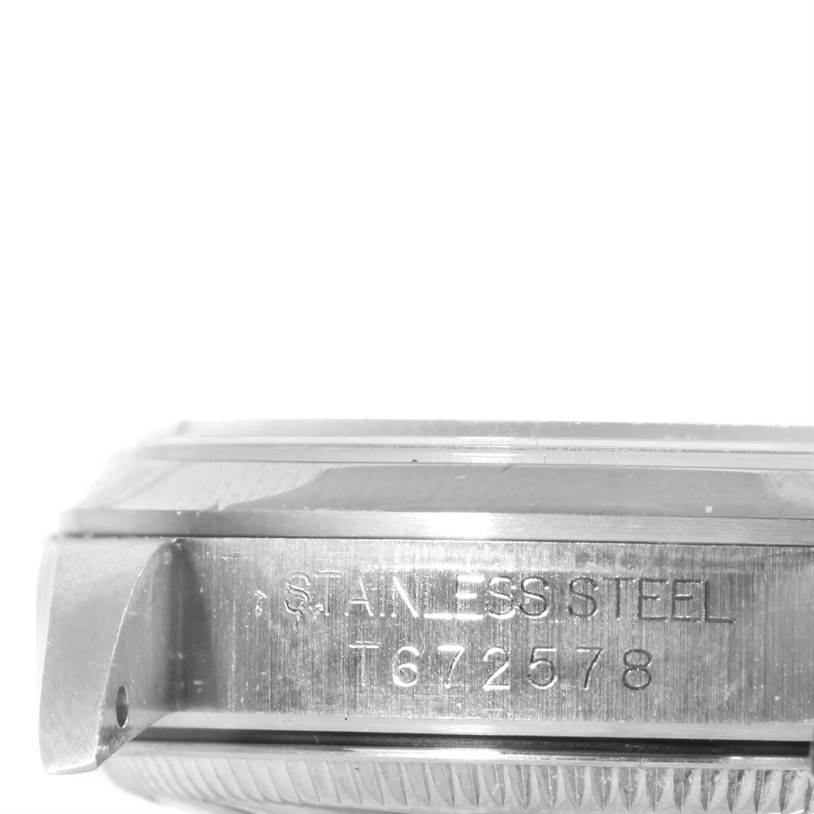 The image shows a close-up, side view of a Rolex Mid-Size 67480 Women's Stainless Steel Blue Dial 67480 Women's Stainless Steel Blue Dial model watch case, highlighting the serial number and stainless steel engraving.