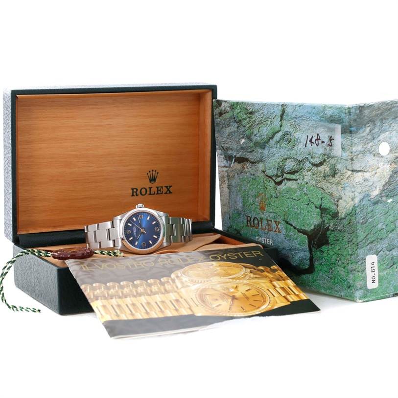 This image shows a Mid-Size Rolex watch with a blue dial, presented in its open box alongside the original packaging and booklet.