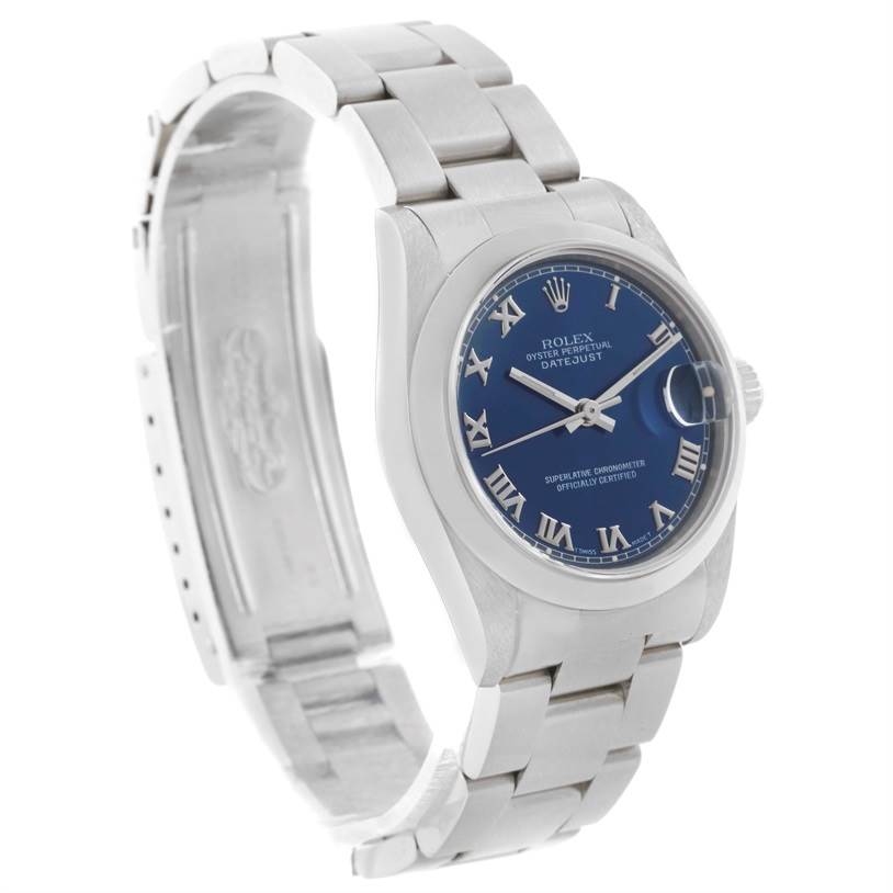 The image shows a side-angle view of a Mid-Size Rolex Datejust, displaying its blue dial and stainless steel bracelet.