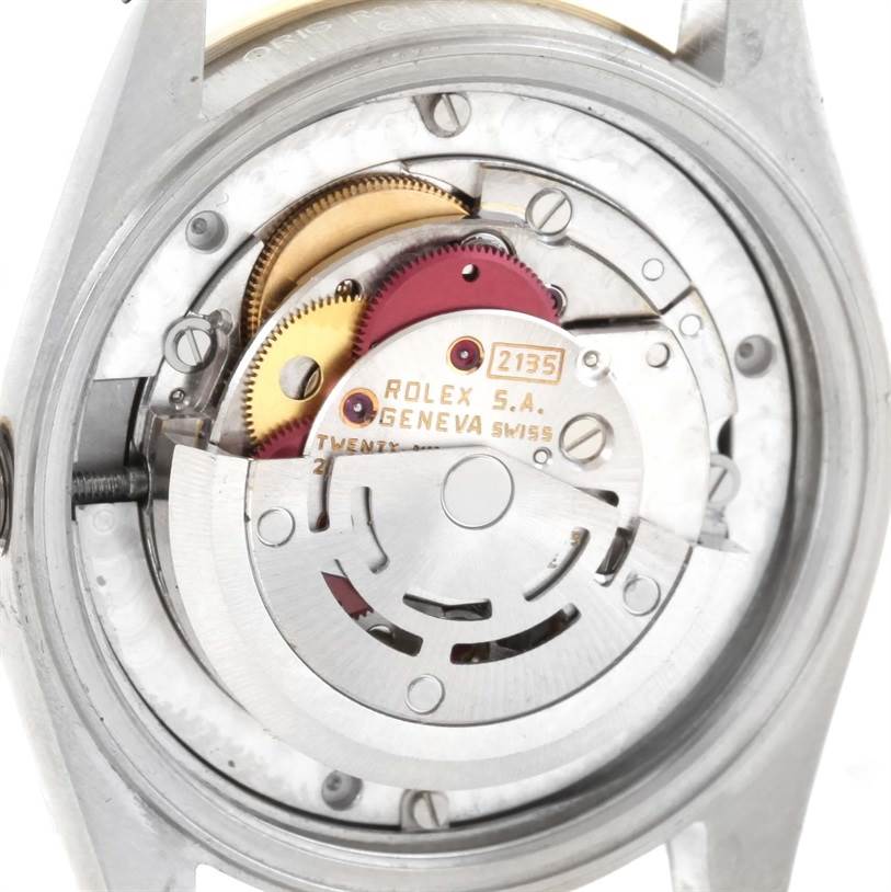 The image shows a close-up view of the movement inside a Mid-Size Rolex watch, highlighting its gears and rotary mechanism.