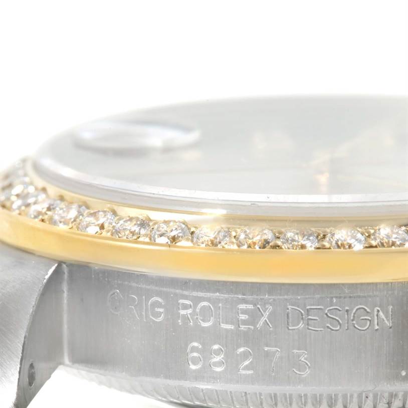 The image shows a side angle of a Mid-Size Rolex watch, focusing on the diamond-set bezel and the engraved case design.