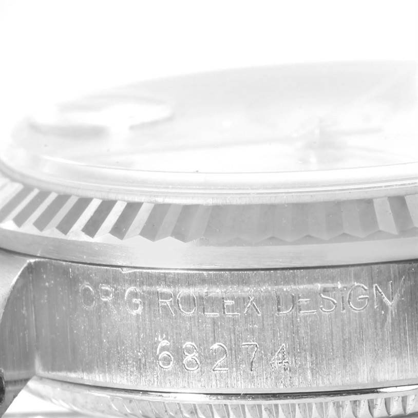 The image shows a close-up angle of the side of the Rolex Mid-Size 68274 Women's Stainless Steel White Dial 68274 Women's Stainless Steel White Dial model, displaying the bezel, crystal, and engraved case details.