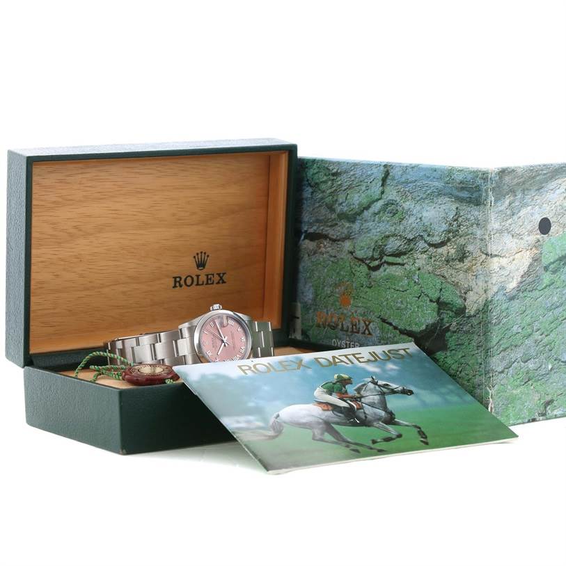 The image shows a mid-size Rolex watch inside its open box, along with a Rolex Datejust booklet.