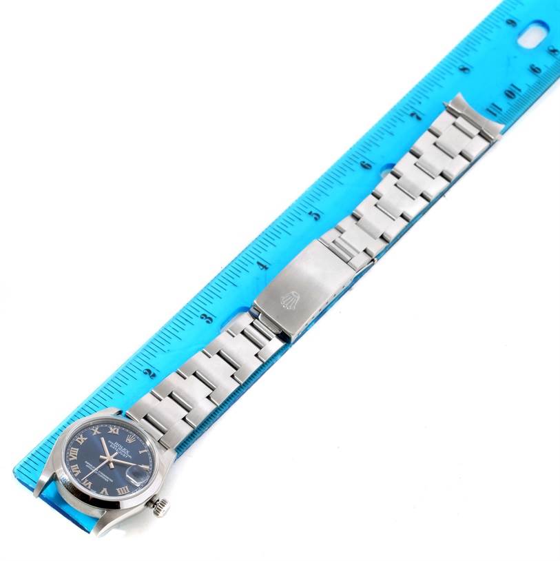 The image shows a Mid-Size Rolex watch laid flat, displaying the dial, case, bracelet, and clasp, measured against a blue ruler.