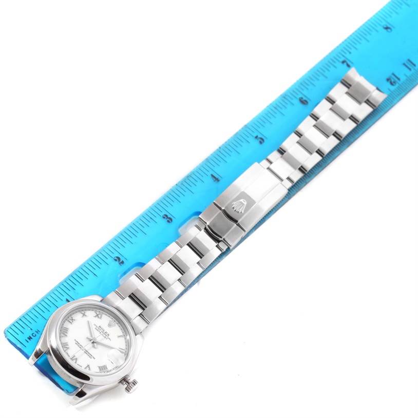 The image shows a top-down view of a Rolex Mid-Size 178240 Women's Stainless Steel White Dial 178240 Women's Stainless Steel White Dial watch, including its face, bracelet, and clasp, alongside a ruler for scale.