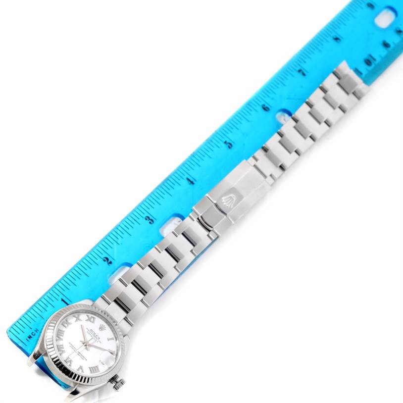 The image shows a Rolex Mid-Size 178274 Women's Stainless Steel White Dial 178274 Women's Stainless Steel White Dial watch face-up with its bracelet fully extended next to a blue ruler.