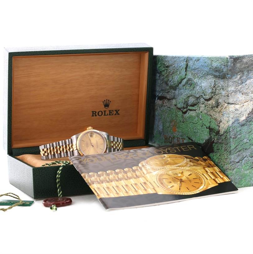 The image shows a Mid-Size Rolex watch with a silver and gold bracelet, its box, a manual, and tags at an angled view.