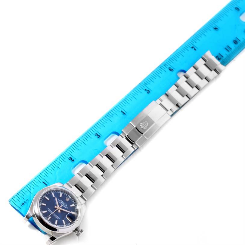 The image shows a blue dial and metal bracelet of a Rolex Mid-Size 178240BLSO Women's Stainless Steel Blue Dial 178240BLSO Women's Stainless Steel Blue Dial watch alongside a blue ruler, viewed from above.
