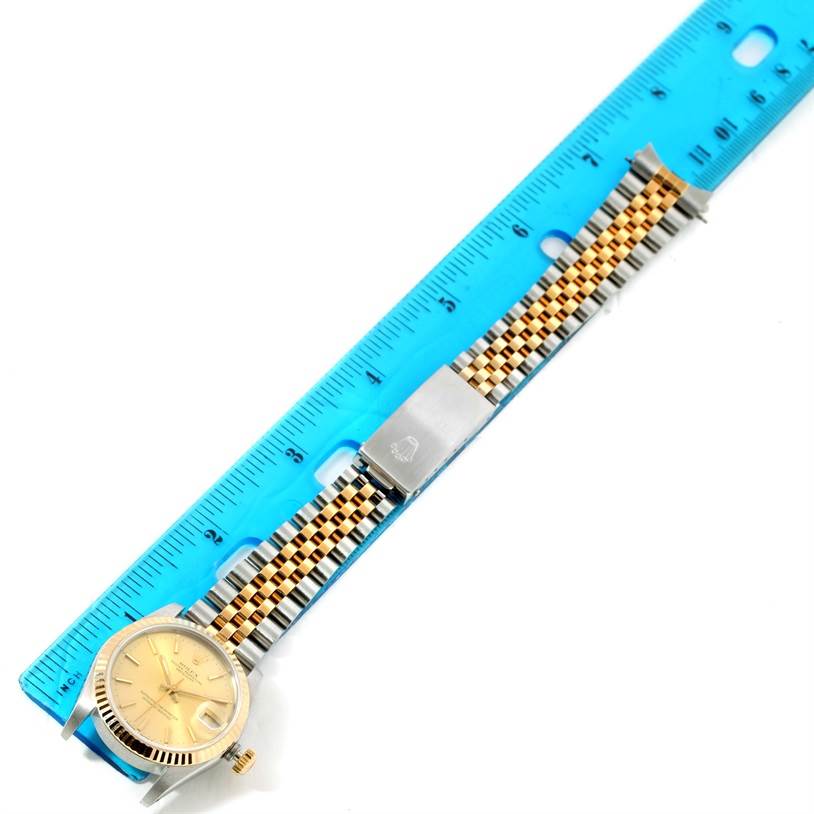 The Rolex Mid-Size 68273 Women's Steel and Gold (two tone) Champagne Dial 68273 Women's Steel and Gold (two tone) Champagne Dial model watch is shown from a top-down angle, with its face, band, and a measuring ruler.