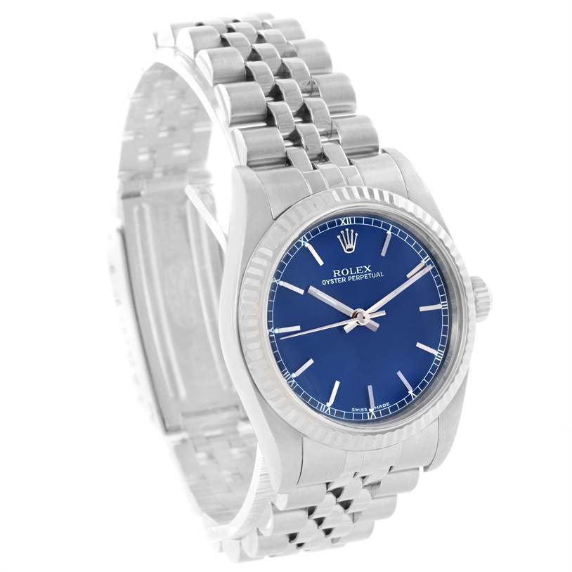 The image shows a Rolex Oyster Perpetual Mid-Size watch from an angled front view, revealing its blue dial, case, and metal bracelet.