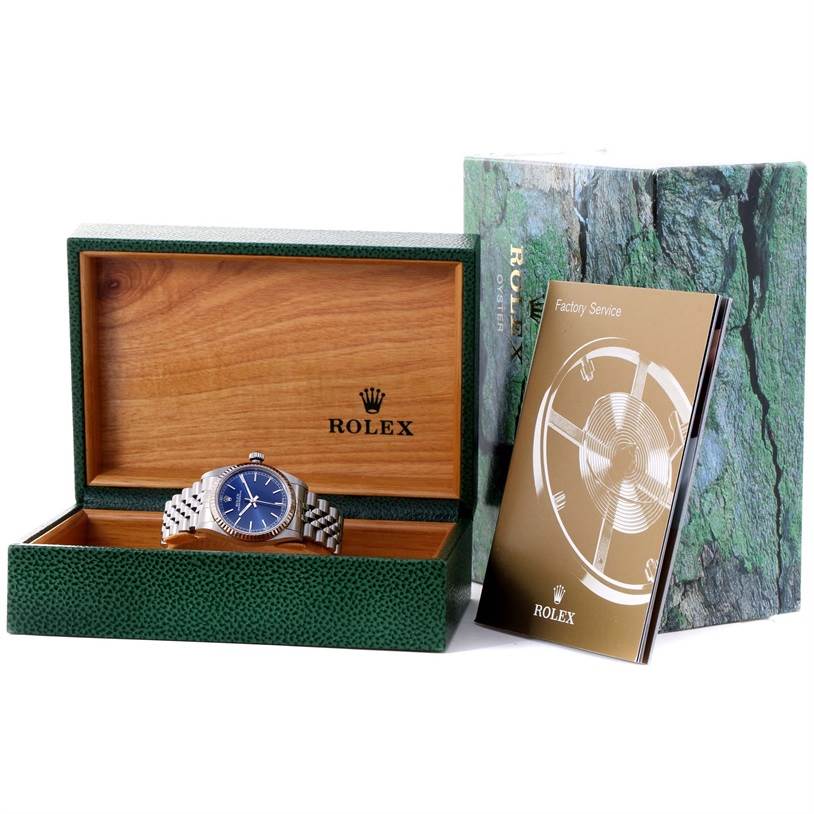The image shows a Rolex Mid-Size 77014 Women's Stainless Steel Blue Dial 77014 Women's Stainless Steel Blue Dial watch inside its open box, with the outer box and an accompanying booklet beside it.