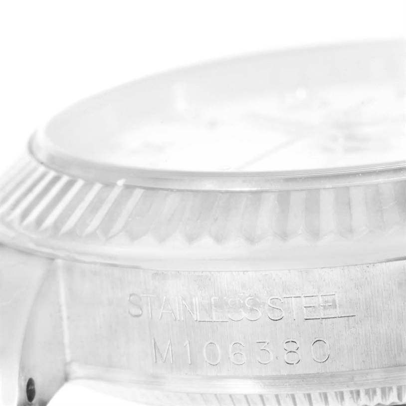 The image shows a close-up of the bezel and the case side of a mid-size Rolex watch, highlighting the stainless steel marking and reference number.