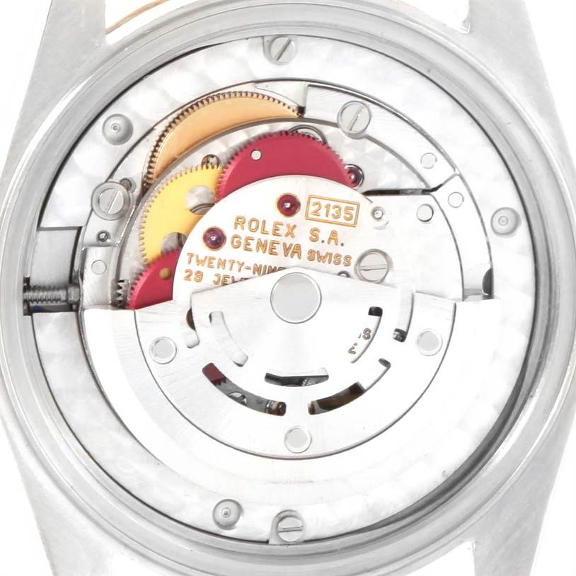 This image shows the internal mechanism of a Mid-Size Rolex watch from a rear angle, highlighting the gears and movement parts.