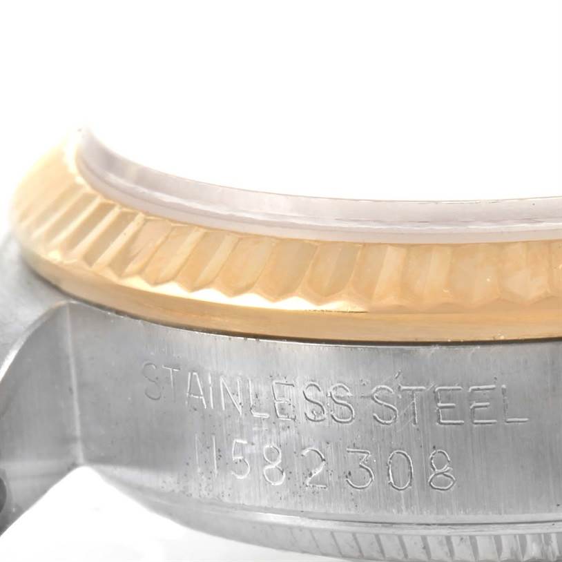 This close-up image of a Rolex Mid-Size 68273 Women's Steel and Gold (two tone) Champagne Dial 68273 Women's Steel and Gold (two tone) Champagne Dial watch shows part of the stainless steel case with the serial number and a portion of the bezel.