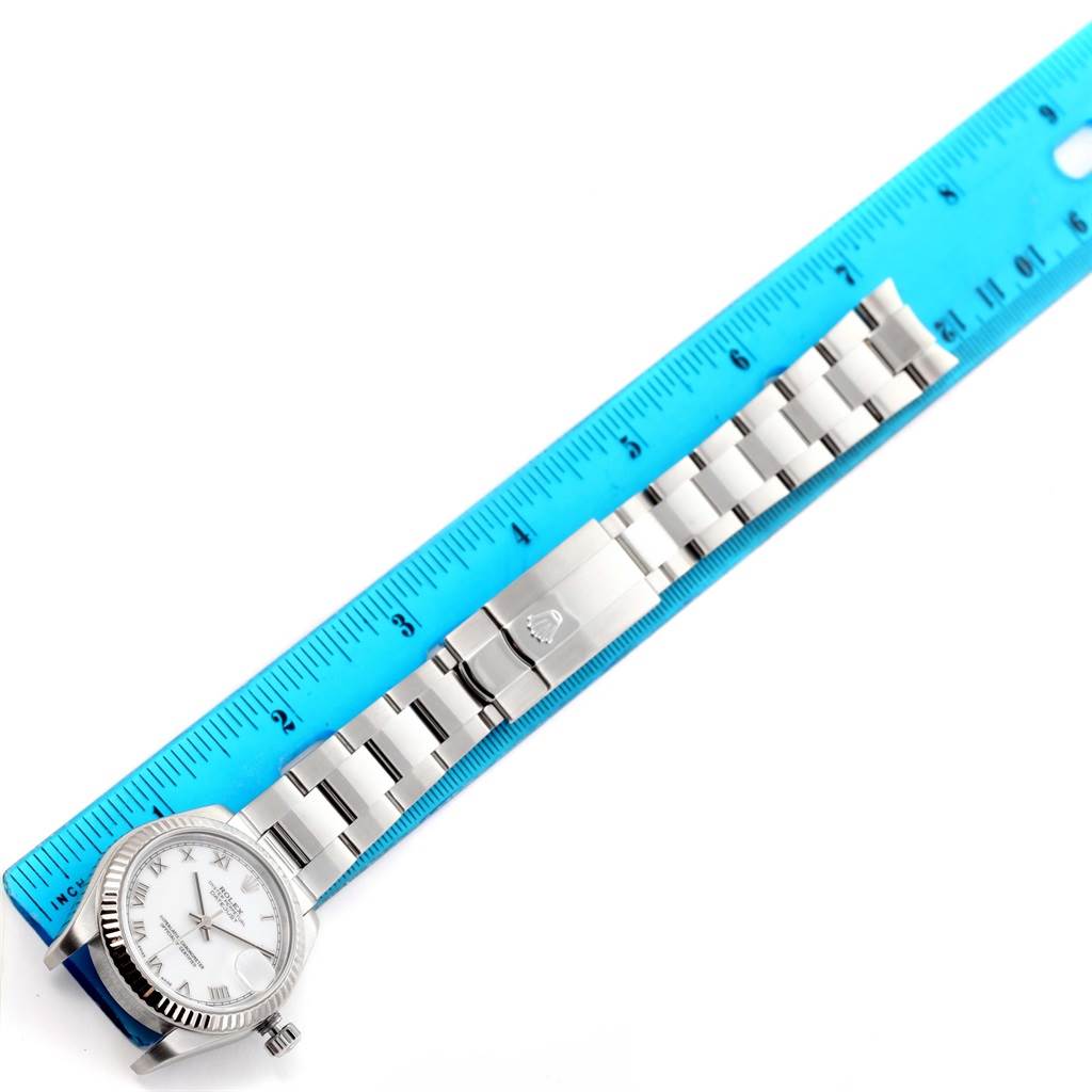 The image shows the Rolex Mid-Size 178274 Women's Stainless Steel White Dial 178274 Women's Stainless Steel White Dial watch laid next to a blue ruler, highlighting its bracelet and clasp.