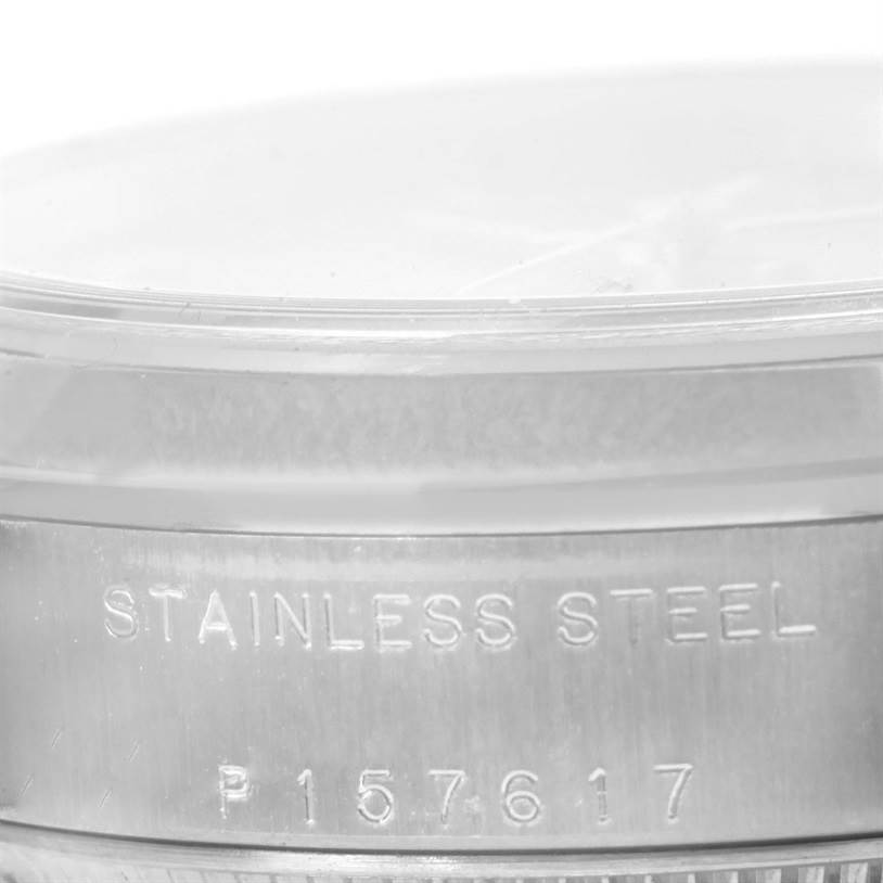 This is a close-up view of the side of a Mid-Size Rolex watch, showing the "STAINLESS STEEL" engraving and serial number.