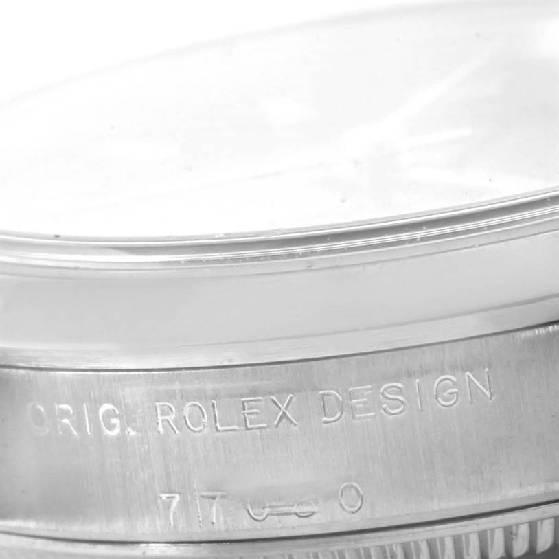This image shows a close-up of the side of a Rolex Mid-Size 77080 Women's Stainless Steel Blue Dial 77080 Women's Stainless Steel Blue Dial model watch, highlighting the engraving and part of the bezel.