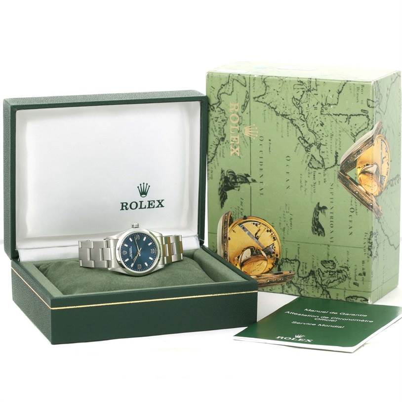 This Rolex Mid-Size 77080 Women's Stainless Steel Blue Dial 77080 Women's Stainless Steel Blue Dial watch is shown from the front and comes with its box, manual, and warranty booklet.