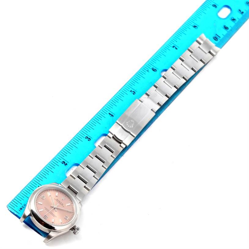 The Rolex Mid-Size 177200 Women's Stainless Steel Pink Dial 177200 Women's Stainless Steel Pink Dial watch is displayed flat, showing the face, bracelet, and clasp against a blue ruler for measurement.