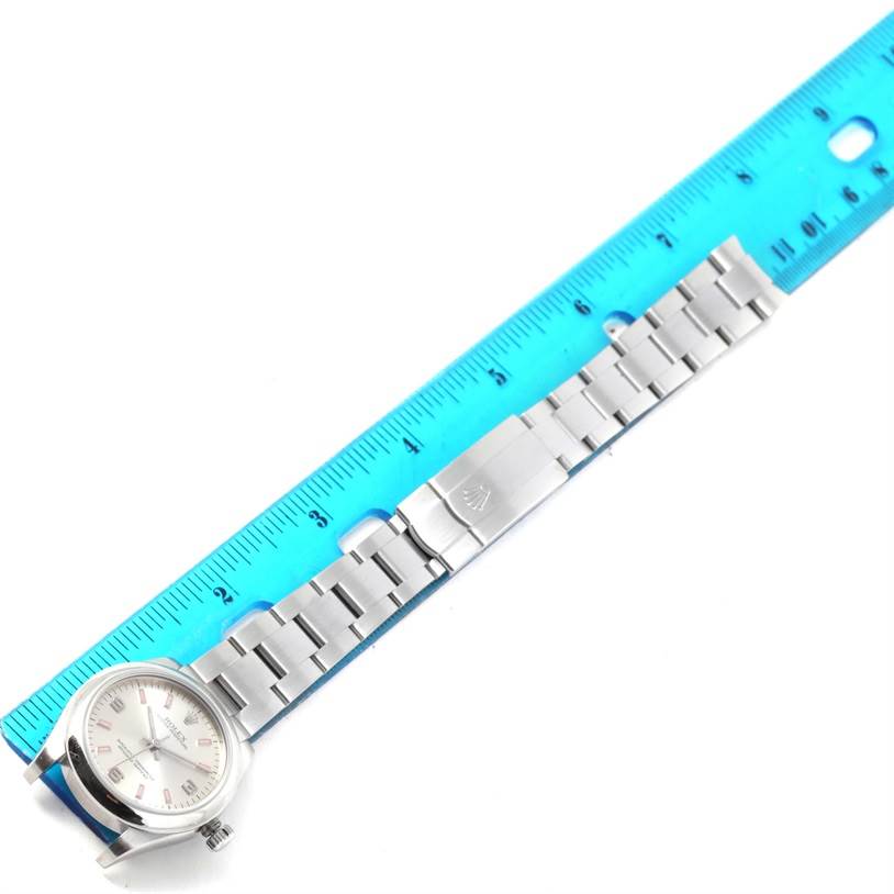 The image shows a side view of a Mid-Size Rolex watch and its bracelet, positioned beside a blue ruler for scale.
