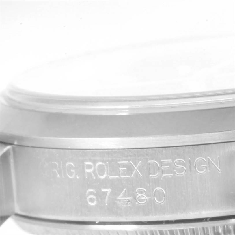 The image shows a close-up of the side of a Rolex Mid-Size 67480 Women's Stainless Steel Black Dial 67480 Women's Stainless Steel Black Dial model watch, focusing on the engraving "ORIG. ROLEX DESIGN 67480".