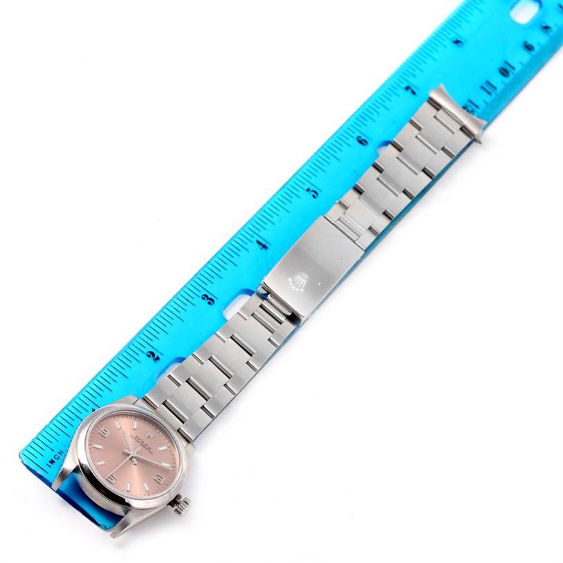 The image shows a Rolex Mid-Size 77080 Women's Stainless Steel Pink Dial 77080 Women's Stainless Steel Pink Dial watch laying flat next to a blue ruler, displaying the watch case, dial, bracelet, and clasp.