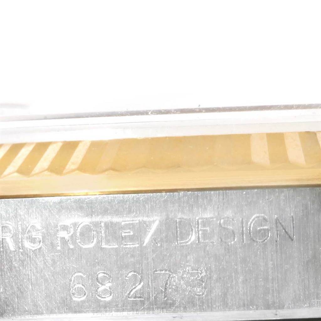 The image shows an engraved side profile of a Rolex Mid-Size 68273 Women's Steel and Gold (two tone) Silver Dial 68273 Women's Steel and Gold (two tone) Silver Dial model watch, featuring the bezel and part of the case.