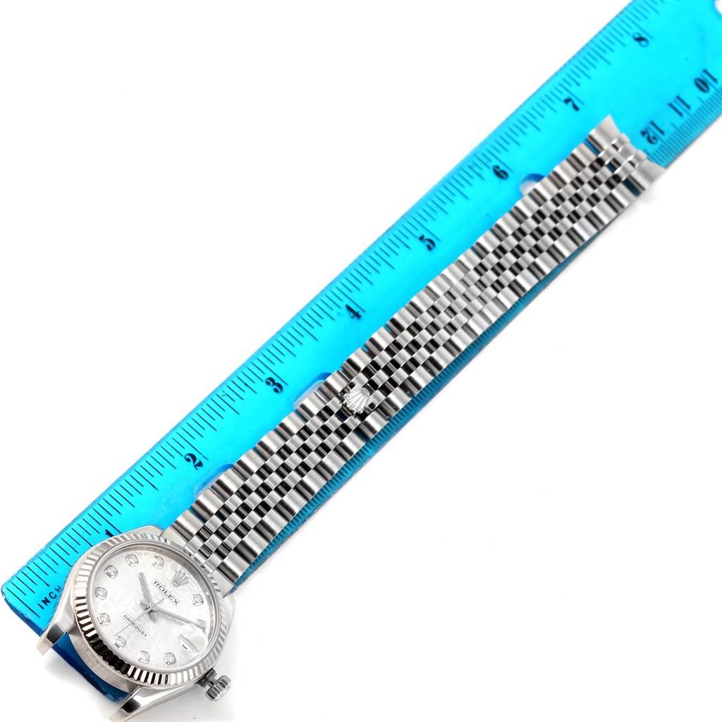 The Rolex Mid-Size 178274 Women's Stainless Steel Silver Dial 178274 Women's Stainless Steel Silver Dial watch is shown from a top-down angle, displaying the face, case, and full bracelet alongside a ruler.