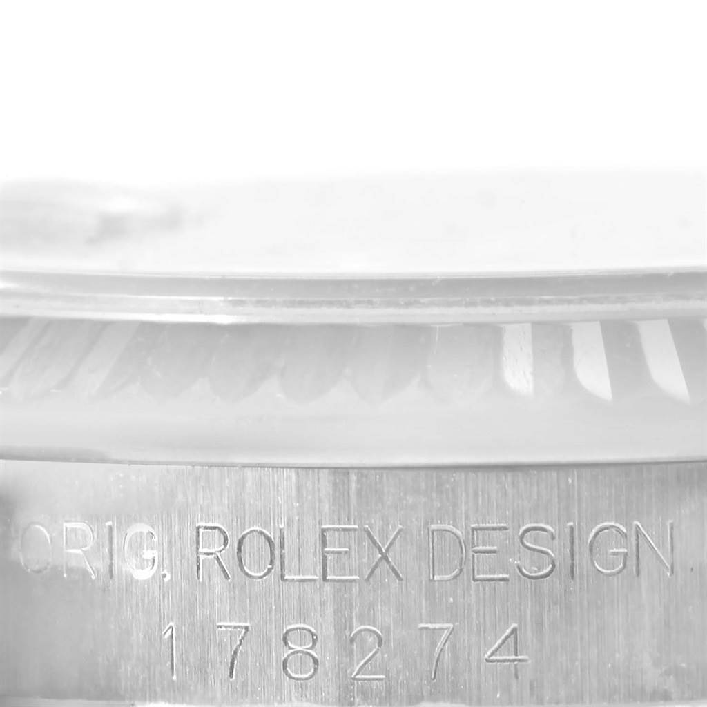 The image shows a close-up of the bezel and engraved case of a Rolex Mid-Size 178274 Women's Stainless Steel Black Dial 178274 Women's Stainless Steel Black Dial model, focusing on the watch's design details.