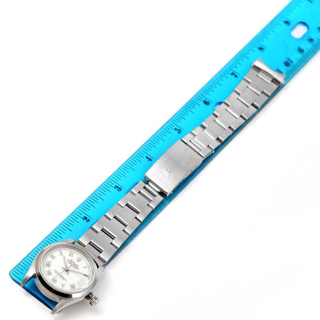 The image shows a Mid-Size Rolex watch with its bracelet fully extended, laid next to a blue ruler for measurement.