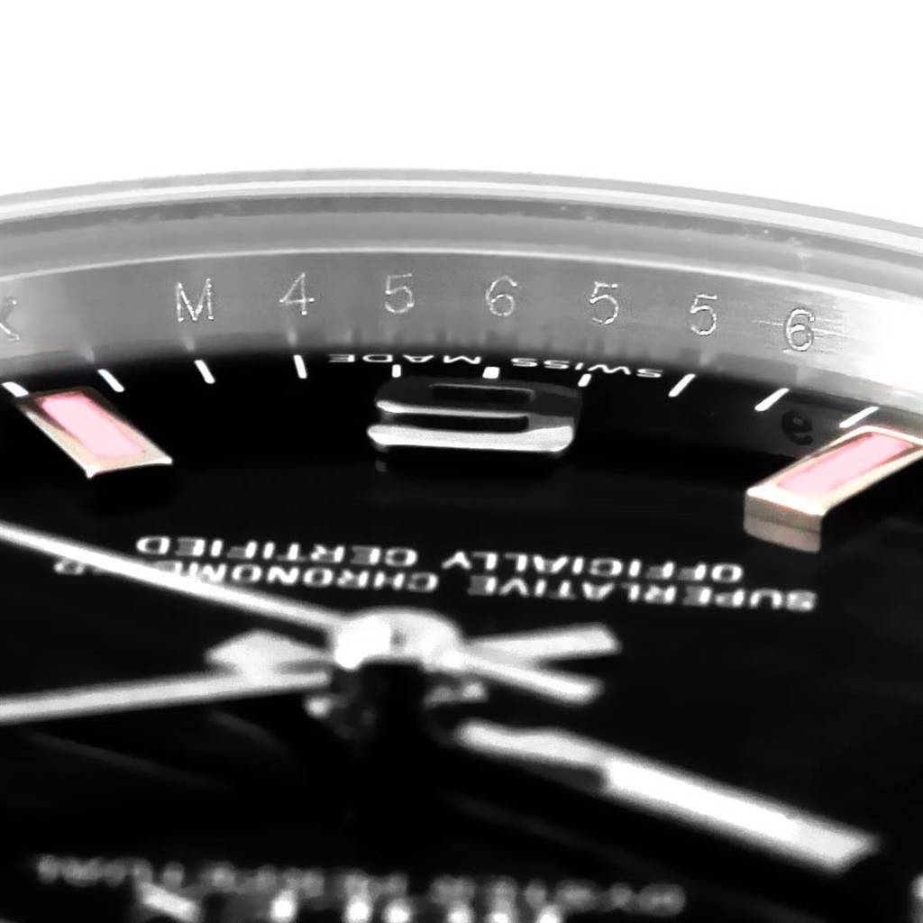 This close-up image of a Mid-Size Rolex watch shows part of the bezel, dial, and hands at a low angle.