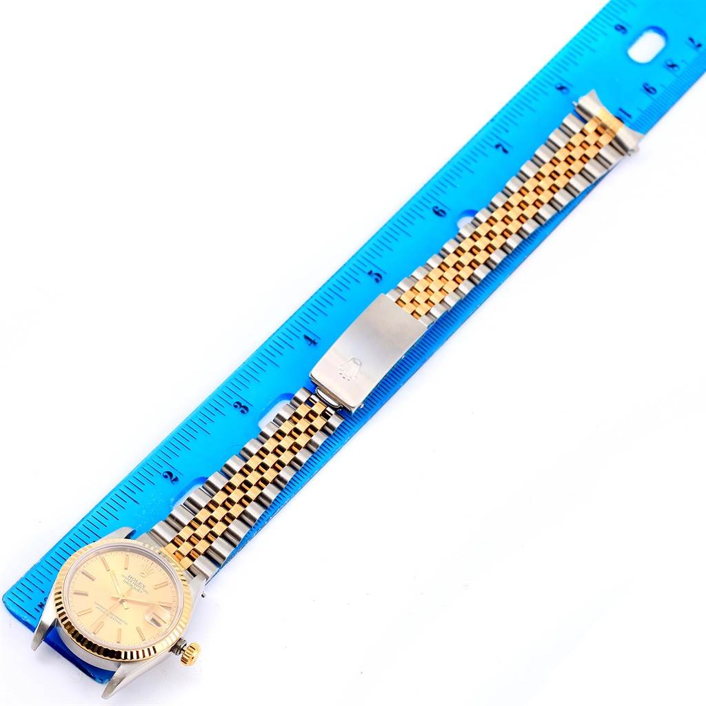 The image shows a Mid-Size Rolex watch laid flat next to a ruler, displaying the watch face and full bracelet.