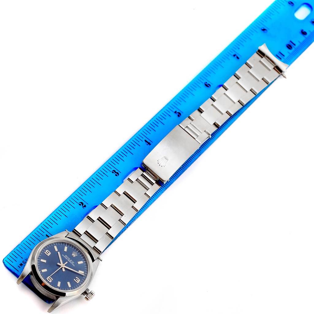 The Rolex Mid-Size 77080 Women's Stainless Steel Blue Dial 77080 Women's Stainless Steel Blue Dial watch is shown from a top-down angle, displaying the watch face, bracelet, and clasp alongside a blue ruler.