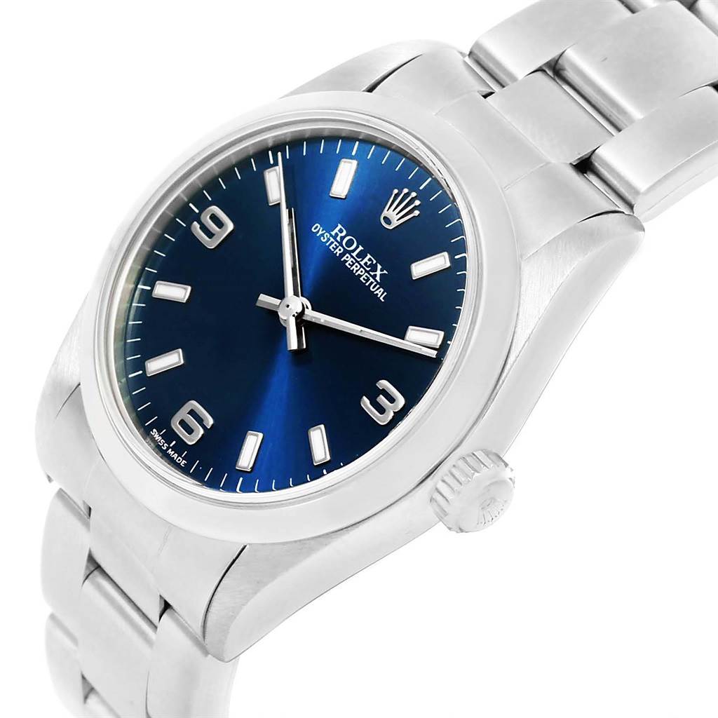 This image shows a close-up angled view of a Rolex Oyster Perpetual Mid-Size watch, highlighting its blue dial and stainless steel bracelet.