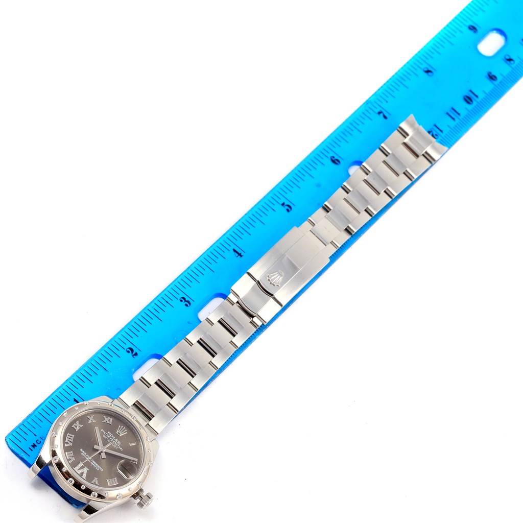 The image shows a Rolex Mid-Size 178344 Women's Stainless Steel Brown Dial 178344 Women's Stainless Steel Brown Dial model watch laid flat with its band next to a ruler.