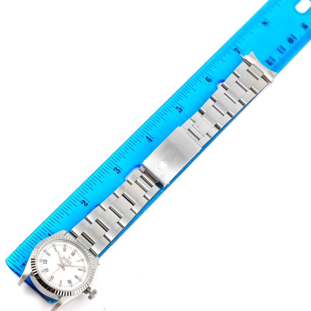 The image shows a Rolex Mid-Size 67514 Women's Stainless Steel White Dial 67514 Women's Stainless Steel White Dial model watch laid flat next to a blue ruler, displaying its band and face.