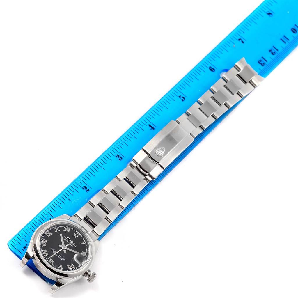 The image shows a Rolex Mid-Size 178240 Women's Stainless Steel Black Dial 178240 Women's Stainless Steel Black Dial watch from a top-down angle, featuring its dial, bracelet, and clasp with a blue ruler for scale.