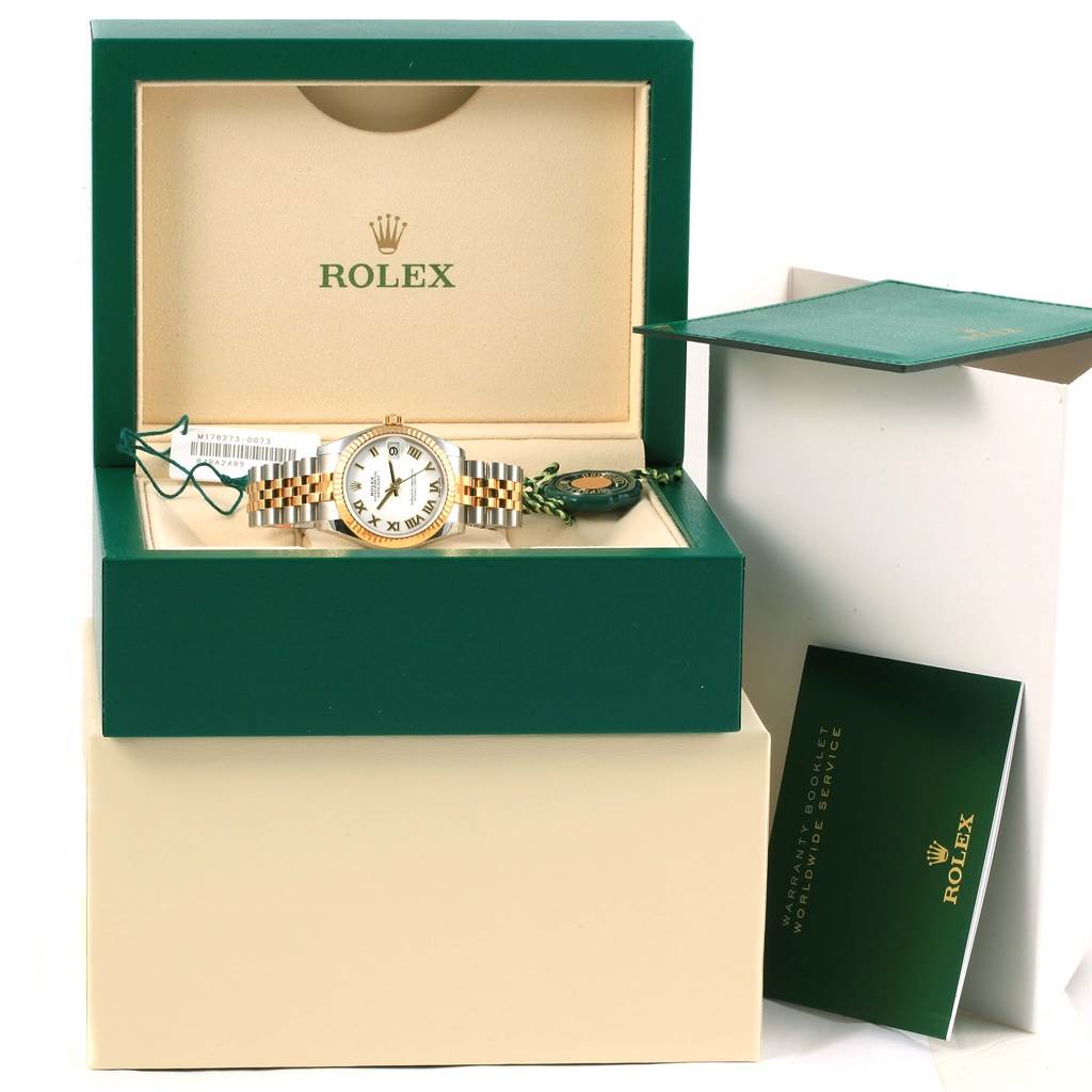 The Mid-Size Rolex watch is displayed frontally inside a green and beige box with accessories including a booklet and tags.