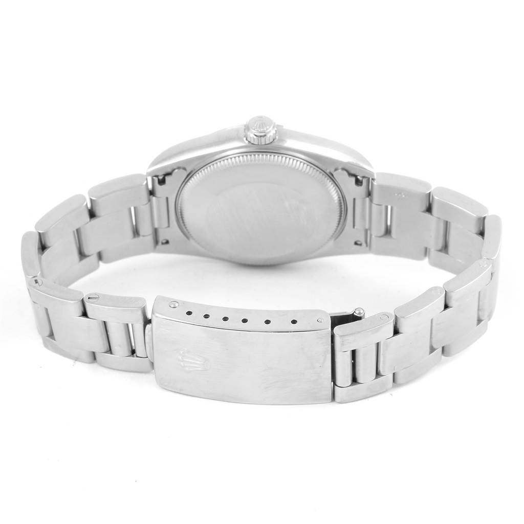 The image shows the back view of a mid-size Rolex watch with focus on its case back, crown, and metal bracelet with a clasp.