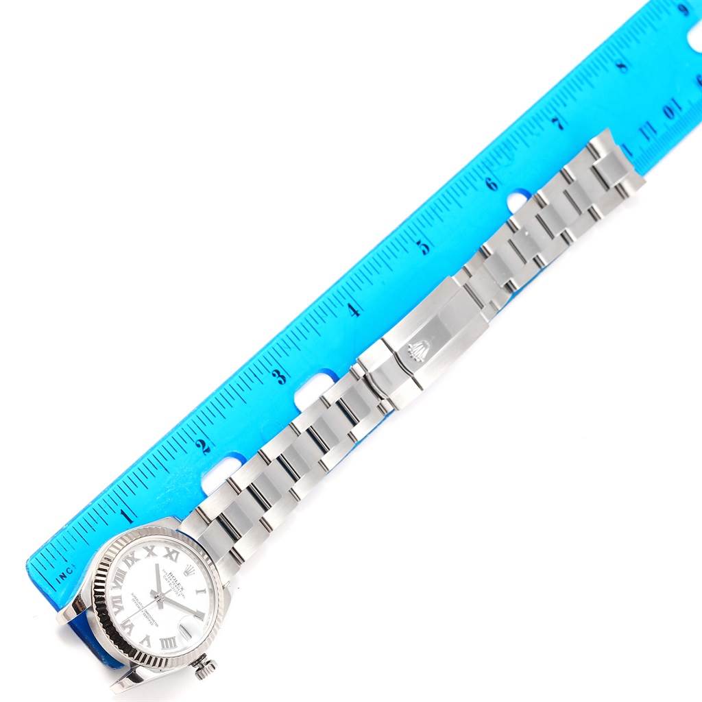 The image shows a Rolex Mid-Size 178274 Women's Stainless Steel White Dial 178274 Women's Stainless Steel White Dial watch laid flat next to a ruler, displaying its dial, strap, and clasp.