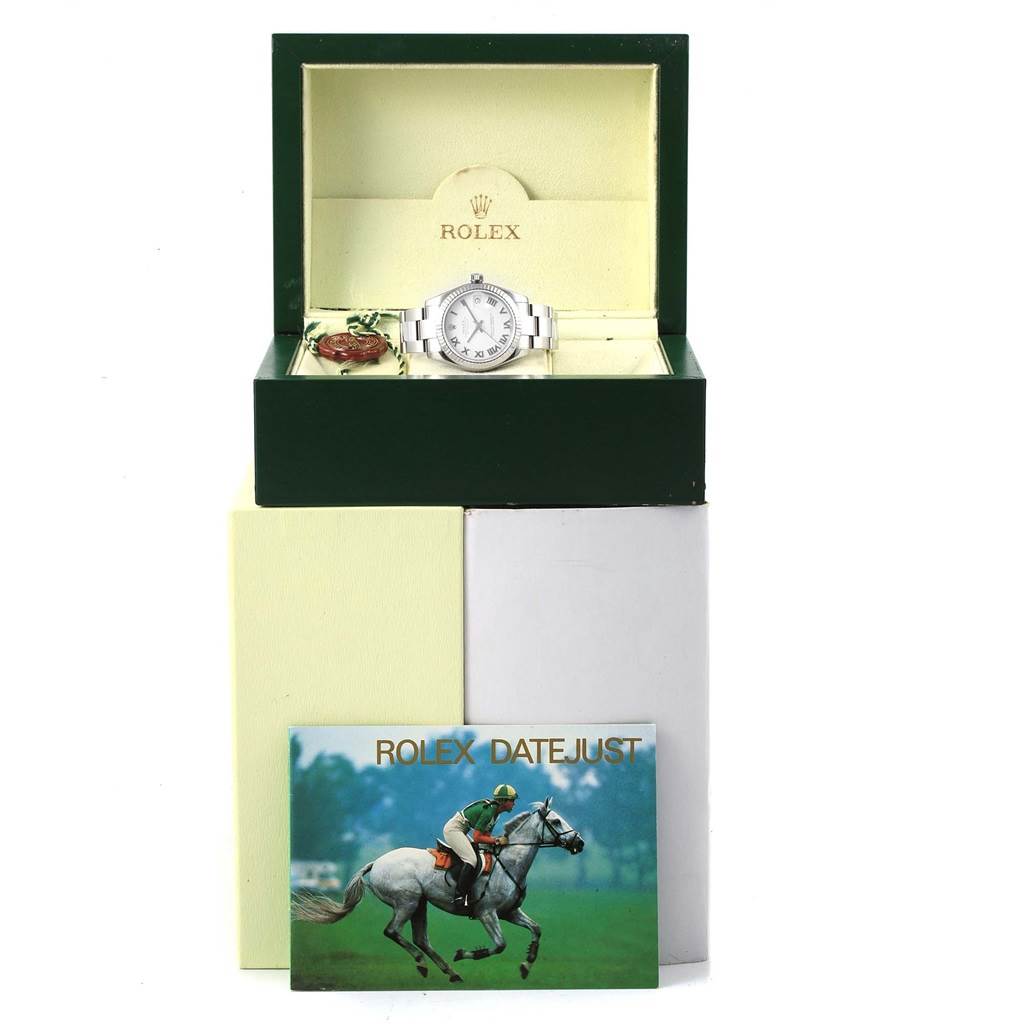 The Rolex Mid-Size 178274 Women's Stainless Steel White Dial 178274 Women's Stainless Steel White Dial watch is displayed front-facing in an open box with accessories beside it and a brochure in front.