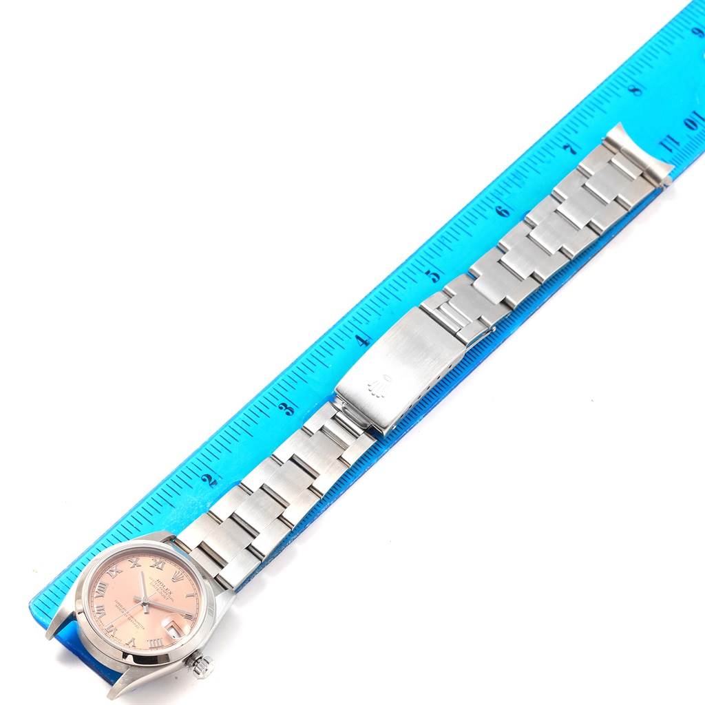 The Rolex Mid-Size 78240 Women's Stainless Steel Pink Dial 78240 Women's Stainless Steel Pink Dial model watch is placed next to a ruler, showing the face, bracelet, and clasp from a top-down angle.