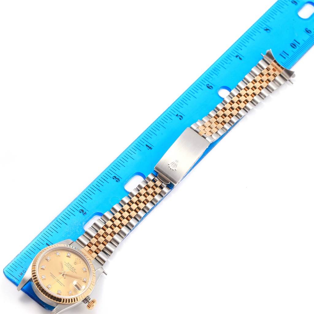 The image shows a Rolex Mid-Size 68273 Women's Steel and Gold (two tone) Champagne Dial 68273 Women's Steel and Gold (two tone) Champagne Dial watch laid flat next to a measuring ruler, featuring its dial, crown, and bracelet.