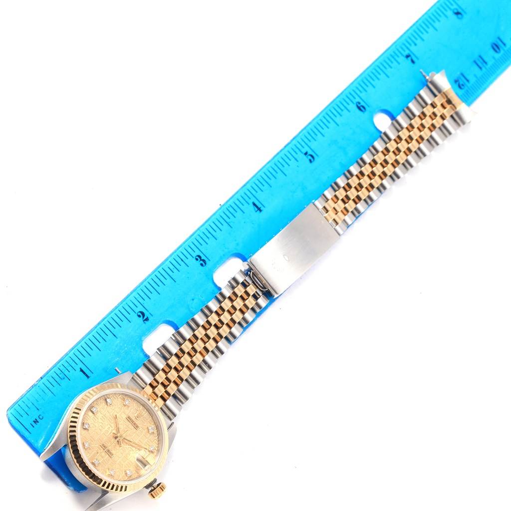 The image shows a top-down view of a Mid-Size Rolex watch with a Jubilee bracelet next to a blue ruler for scale.
