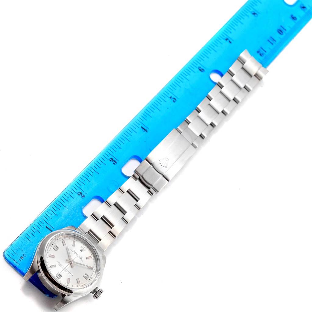 The Rolex Mid-Size 177200 Women's Stainless Steel Silver Dial 177200 Women's Stainless Steel Silver Dial watch is shown from above, featuring the watch face, bracelet, and clasp, next to a blue ruler for scale.