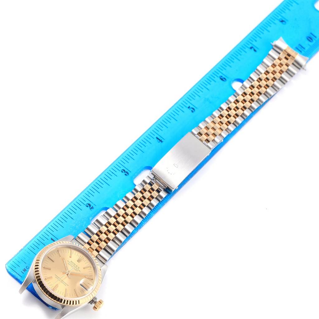 This image shows a full view of a Rolex Mid-Size 68273 Women's Steel and Gold (two tone) Champagne Dial 68273 Women's Steel and Gold (two tone) Champagne Dial watch placed next to a ruler, displaying its face, bezel, and band.